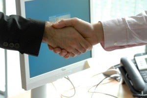 a handshake in front of a computer screen